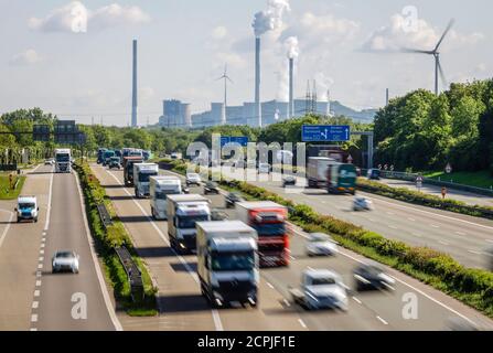 Muchos camiones conducen por la autopista A2, en la parte trasera de la planta de carbón Gelsenkirchen Scholven, a la derecha un aerogenerador, la industria y el tráfico en Foto de stock