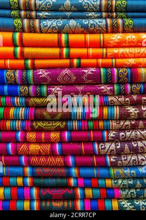 Un montón de coloridos textiles tradicionales en el mercado dominical de los Andes de Otavalo, al norte de Quito, Ecuador. Foto de stock