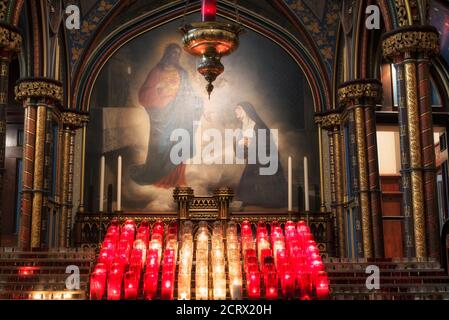 Un pequeño altar de velas delante de una pintura de jesús dentro del histórico altar de la catedral de notre dame en el Viejo Montreal Quebec Canadá iluminado con azul y.