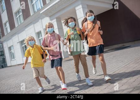 Escolares en máscaras protectoras en su camino a casa después de las clases