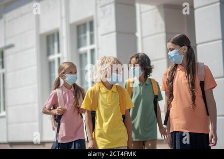 Escolares en máscaras protectoras en su camino a casa después de la escuela