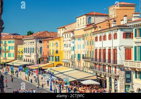 Verona, Italia, 12 de septiembre de 2019: Fila de viejos edificios coloridos y coloridos en la plaza Piazza Bra en el centro histórico de la ciudad, cafés y restaurantes con tiendas de campaña y turistas caminando, vista aérea