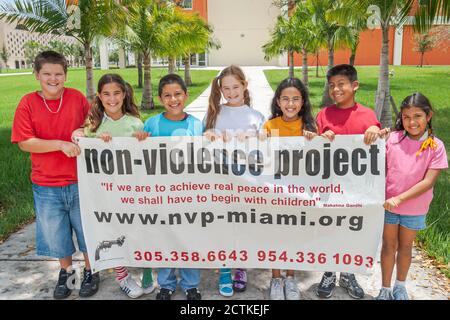Miami Florida,Proyecto No Violencia USA,enseñar comportamiento no violento a estudiantes, niños niñas niñas sonrisas sonriendo,sostener banner,hispano Foto de stock