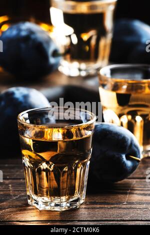 Slivovica - brandy de ciruela o vodka de ciruela, licor de los Balcanes, bebida fuerte en vasos de tiro en la vieja mesa de madera, espacio de copia Foto de stock