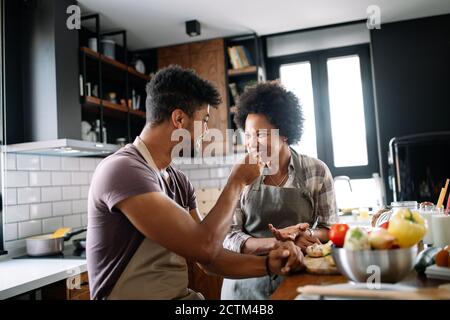 Feliz pareja joven de cocinar juntos en la cocina de casa. Foto de stock