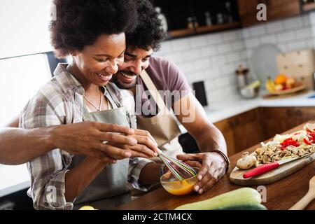 Feliz pareja joven de cocinar juntos en la cocina de casa. Foto de stock