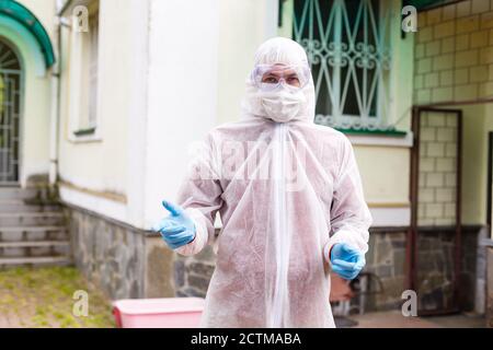 El enfoque selectivo de hombres sonrientes científico en máscara protectora y palo mirando a la cámara en el exterior