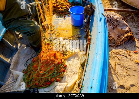 Fisher en pantalones de goma y botas está sentado en su barco y apilar red  de pesca para pescar en mar abierto Fotografía de stock - Alamy
