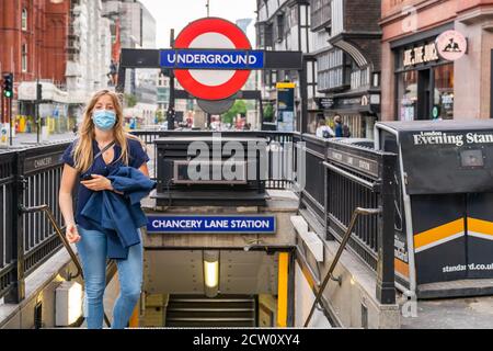 LONDRES, INGLATERRA - 24 DE JULIO de 2020: Joven rubia saliendo de la estación de metro Chancery Lane usando una máscara y llevando su chaqueta durante el Foto de stock