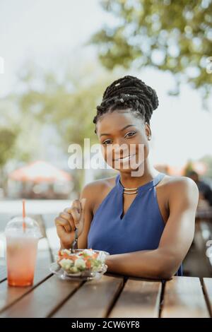 Joven Afroamericana comer ensalada en el café al aire libre Foto de stock