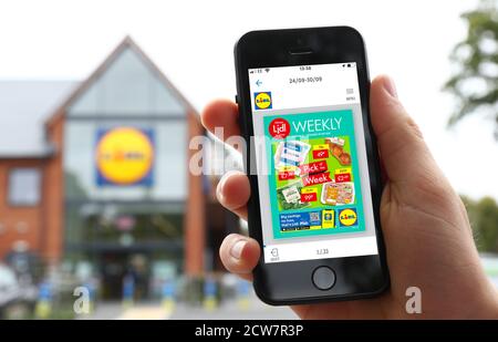 Un hombre usando la aplicación Lidl Plus en su teléfono Fuera de una tienda Lidi en el Reino Unido Foto de stock
