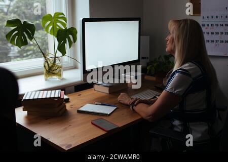 Profesor de formación en línea. Día a día nuevo trabajo normal de oficina desde casa. Sonriente mujer madura que tiene videollamada a través de un ordenador portátil en la oficina del estudio.