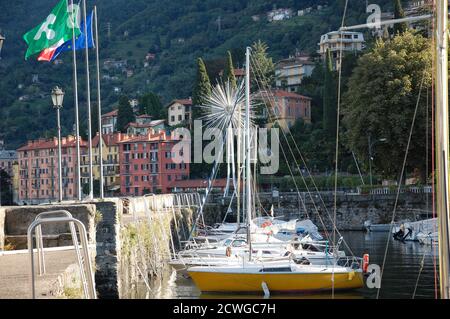 Antiguo puerto deportivo en Bellano en la costa este del lago Como con los barcos atracados y la región de Lombardía bandera de vuelo