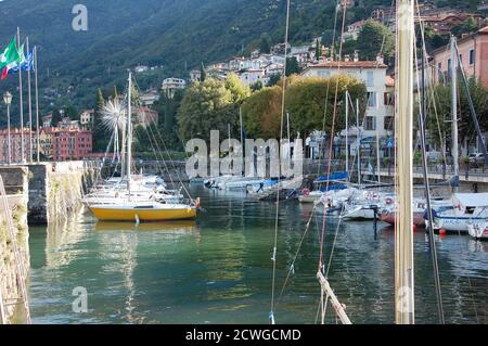 Antiguo puerto deportivo en Bellano en la costa este del lago Como con los barcos atracados y la región de Lombardía bandera de vuelo