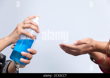 Primer plano de una mujer rociando desinfectante de manos en las manos de otra mujer, Covid 19 protección, distanciamiento social. Foto de stock