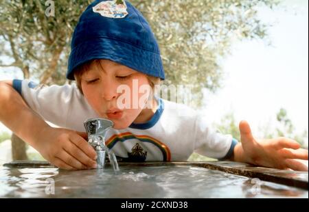 Un niño de cinco años usa una fuente de agua en Jerusalén, Israel, estaciona A UN niño joven bebiendo agua en el Jardín Conmemorativo de las Rosas, Jerusalén, Israel Foto de stock