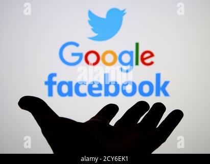 Silueta de mano abierta y Twitter, Google, Facebook logotipos en la pantalla borrosa. Concepto. Foto de stock