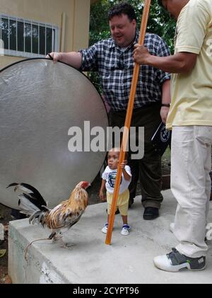 Junrey Balawing se mantiene en un poste junto a un gallo, frente a su padre  Reynaldo (R) y el editor jefe de Guinness World Records Craig Glenday  durante una sesión de toma de fotos en Sindangan, Zamboanga del Norte en el  sur de Filipinas 11 de ...