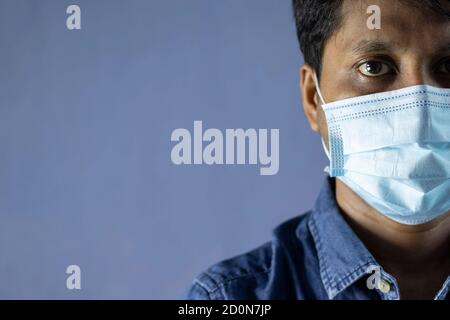 Disparo en la cabeza de un hombre indio con mascarilla quirúrgica de la nariz mirando la cámara para la protección del virus de corona o covid-19