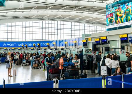 Terminal cinco del aeropuerto de Heathrow, personas con trollies de equipaje en las líneas esperando para registrarse en el mostrador de british Airways B1 a B12. Foto de stock