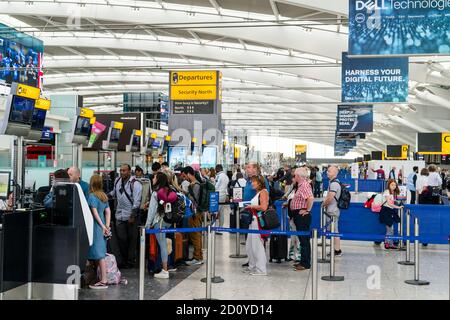 Terminal cinco del aeropuerto de Heathrow, personas con trollies de equipaje en las líneas esperando para registrarse en el mostrador de british Airways B1 en adelante. Foto de stock