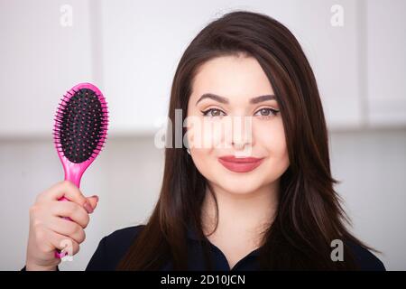 Chica posee un cepillo sin pelo y sonriendo Foto de stock