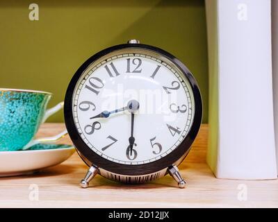 Cumplir orden Hormiga Un reloj despertador con un cuerpo negro y patas plateadas está sobre una  mesa de madera Fotografía de stock - Alamy