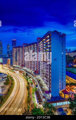 Larga exposición de coches de luz senderos en la ciudad de Singapur contra arquitectura residencial e icónica urbana y patrimonial