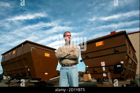 Third-generation farm equipment maker Ric Kirby stands near two cattle  mixer/feeders that sold in Japan, at his farm equipment manufacturing  business in Merced, California October 27, 2009. Since 1837 when blacksmith  John Deere created the first ...