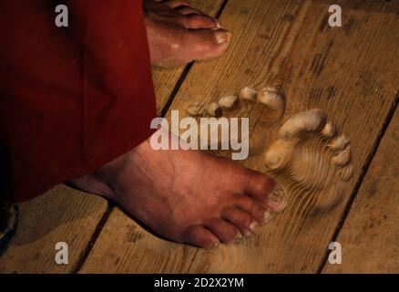 The feet of monk Hua Chi are seen close to the footprints made by him by praying at the same spot for decades, at a monastery near Tongren, Qinghai province February 25, 2009. Hua Chi, who believes he is around 70 years old, has prayed at the same spot so many times that perfect footprints remain on the wooden doorstep. The monk and doctor of traditional medicine has been coming to the small temple in the monastery town of Tongren in China's western Qinghai province for nearly twenty years to perform a strict personal ritual. Every day, before sunrise, Hua arrives at the temple steps, placing 