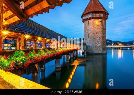 Increíble vida nocturna de Lucerna iluminada por la noche en el lago Lucerna, Suiza. Torre de agua de la histórica pasarela de madera cubierta Puente de Capilla encima