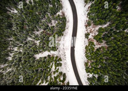Vuelo sobre las montañas de invierno con serpentina carretera y bosque nevado. Vista de arriba hacia abajo. Fotografía de paisajes