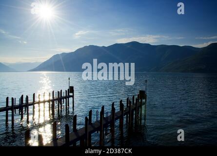 Muelle con Sunbeam y Montaña en el Lago Alpino Maggiore en Ticino, Suiza. Foto de stock