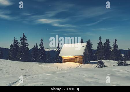 Fantástico paisaje invernal con casa de madera en montañas nevadas. Concepto de vacaciones de Navidad