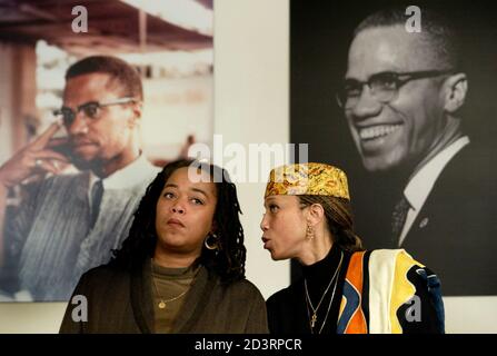 Attallah Shabazz (R) and Malaak Shabazz, two of the six daughters of the  late Malcolm X sit together beneath two portraits of their late father  during a news conference at the New