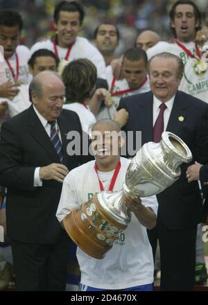 Brazilian captain Alex (C) holds the trophy next to Joseph Blatter (L) FIFA president and Nicolas Leoz (R) president of the South America soccer confederation after Brazil win the Copa America final match against Argentina in Lima, July 25, 2004. Brazil won the match 4-2 in a penalty shootout after the match ended in a tie. REUTERS/Marcos Brindicci  MB