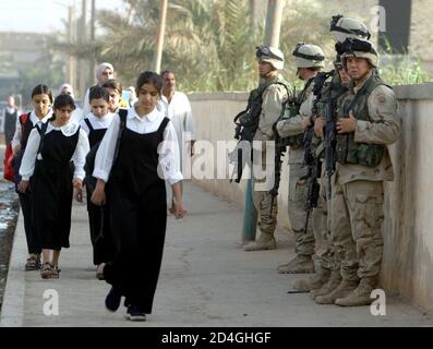 Los soldados del ejército de EE.UU. Están de guardia en la carretera que conduce a una escuela de niñas mientras los alumnos llegan a las clases matutinas en Bagdad, 21 de mayo de 2003. Para respetar las tradiciones locales, se han asignado mujeres soldados a la vecindad inmediata de los establecimientos escolares en un movimiento para ayudar a reducir las barreras culturales. REUTERS/Zohra Bensemra JD/JV