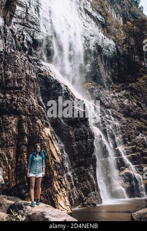 Niña joven de pelo azul de pie bajo la cascada Diyaluma en Sri Lanka. Turista blanco en Asia disfrutando de vacaciones durante la temporada alta. Viajero de aventura
