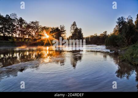 La estrella del sol naciente a través de los árboles alrededor del río Macqarie en la ciudad de Dubbo en Australia.