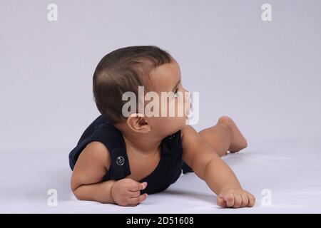 Bebé indio feliz acostado sobre fondo blanco. Foto de stock