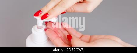 Mujer empuja el dispensador y exprima el gel de jabón suave en la palma, primer plano contra fondo plano. Jabón líquido transparente utilizado para el lavado de manos