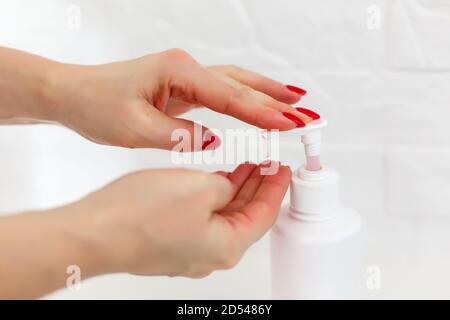 Mujer empuja el dispensador y exprima el gel de jabón suave en la palma, primer plano contra fondo plano. Jabón líquido transparente utilizado para el lavado de manos