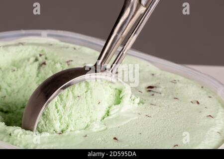 Primer plano de crema de helado de choc de menta siendo recogido por una cuchara mecánica para ser servido. Foto de stock