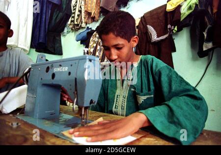 Fares A 13 Year Old Algerian Boy R Is Accompanied By An Unidentified Friend As He Works At A Sewing Machine In The Family Tailors Shop In The Town Of Tamanrasset April