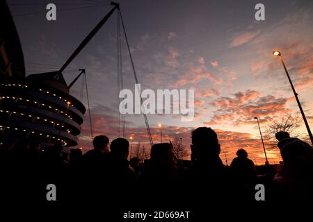 Los aficionados llegan al estadio Etihad mientras el sol se pone antes del partido Foto de stock