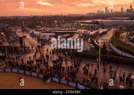 Los aficionados llegan a echar un vistazo al autobús del equipo en el Etihad Stadium mientras el sol se pone antes del partido Foto de stock