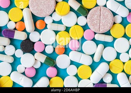 Cierre de píldoras farmacéuticas de colores y tabletas diferentes medicamentos médicos sobre fondo azul. Piso médico laico