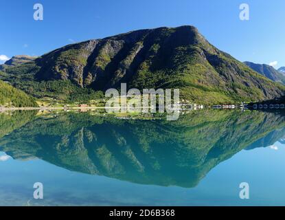 Montañas que se reflejan en el agua tranquila del Dalsfjord cerca Skjolden en un soleado día de verano con un azul claro Cielo y unas pocas nubes Foto de stock