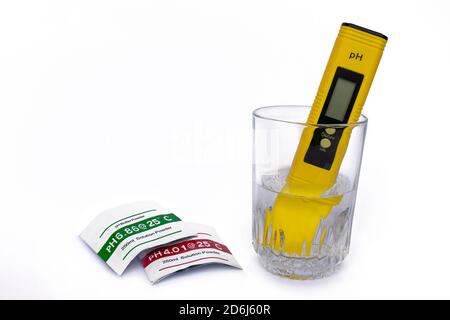 Medidor de pH que mide el pH del agua en el vidrio sobre fondo blanco aislado. Soluciones utilizadas. Foto de stock