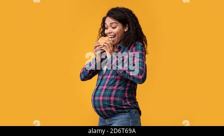 Embarazada Afroamericana comer hamburguesa en el estudio